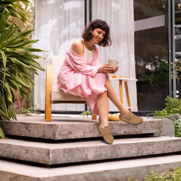 Woman in a pink dress sitting on a chair outdoors, holding a phone.
leather clogs womens
