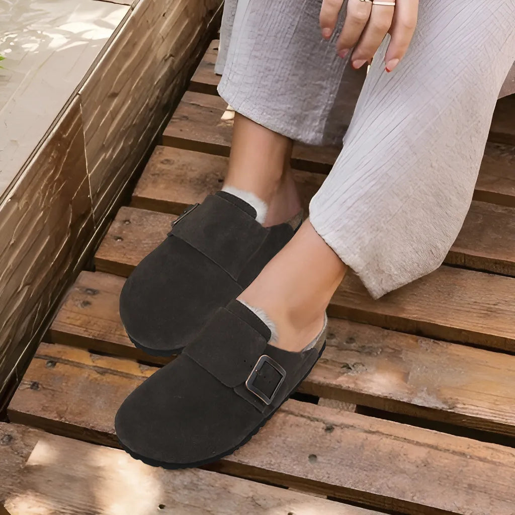 Person wearing black slippers on a wooden floor
leather clogs womens