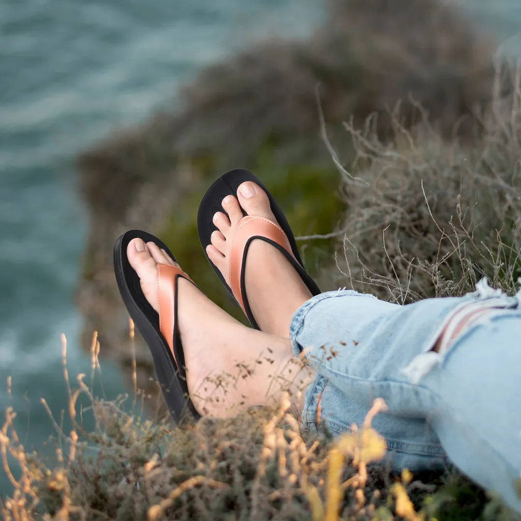 Feet wearing black sandals with orange straps on a grassy cliff overlooking water.
sandals for plantar fasciitis​
best sandals for plantar fasciitis​