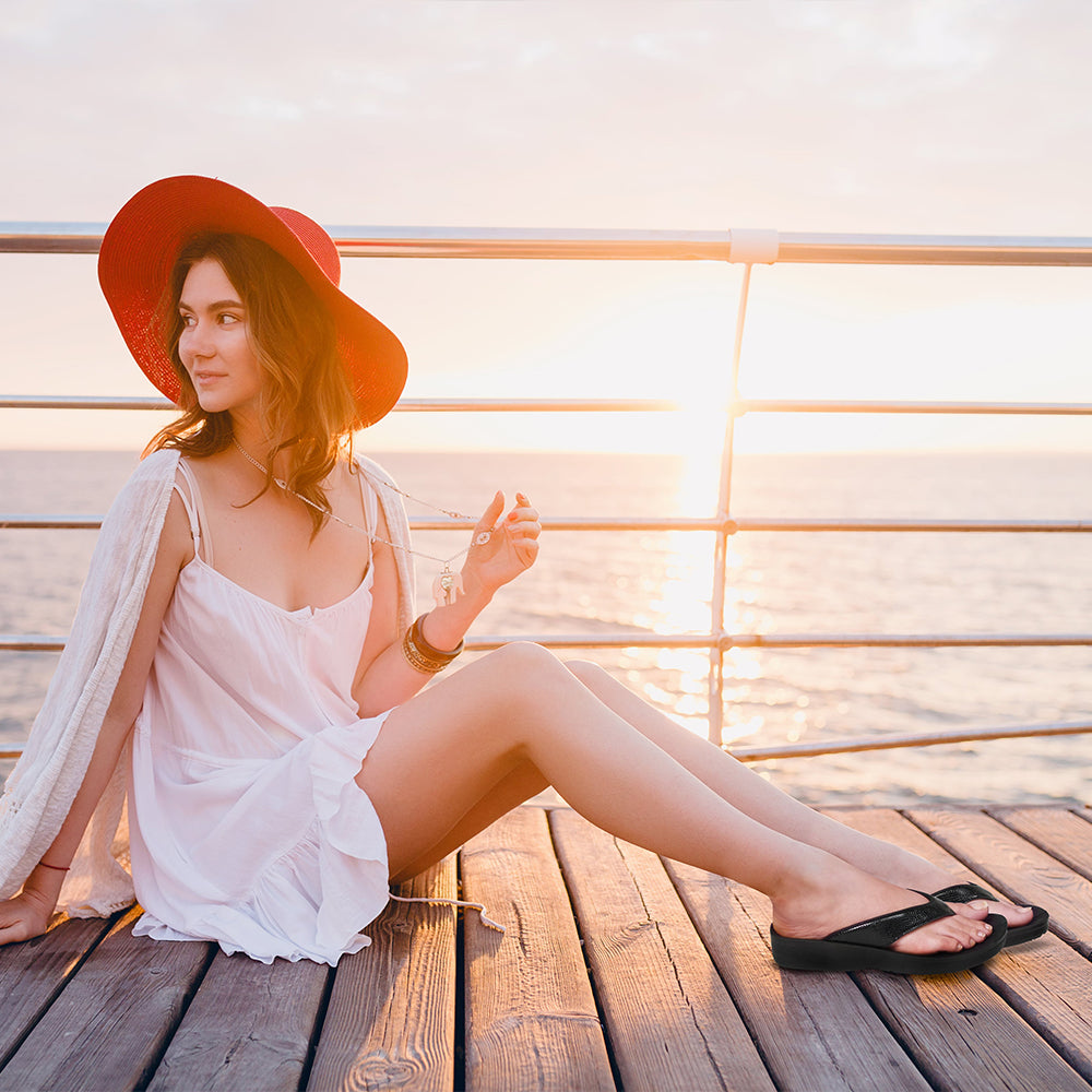 Woman in a white dress and red hat sitting on a wooden deck by the water.
womens thong sandals

