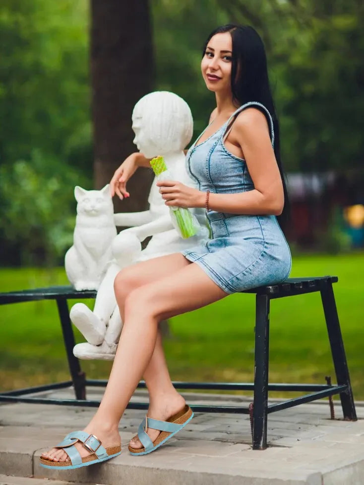 Woman sitting on a bench with white sculptures and a green plant in an outdoor setting
womens cork sandals
cork sandals
cork sandals womens