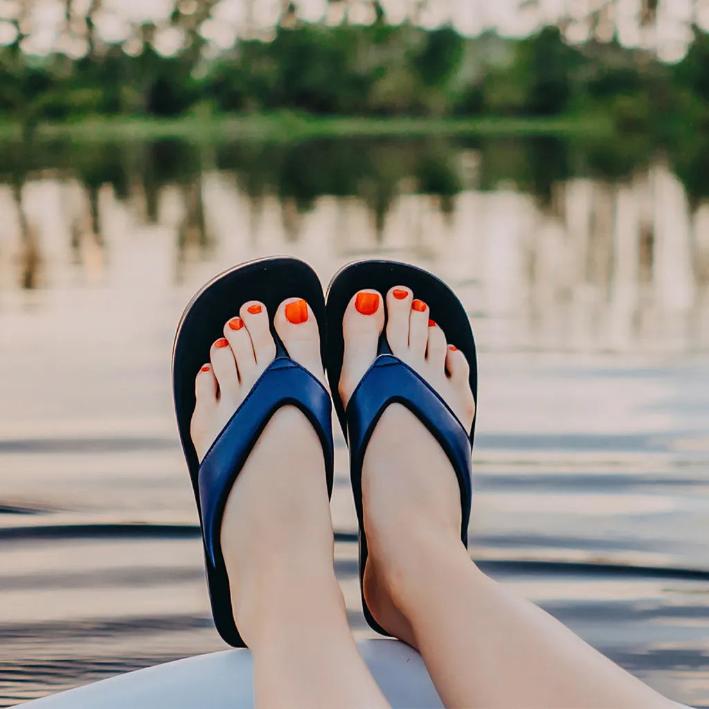 Blue flip-flops with orange nail polish on a blurred natural background
flip flop sandals
arch support thongs