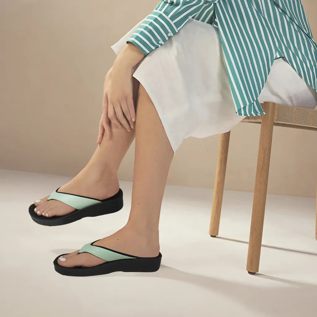 Person wearing black sandals with green straps on a neutral background
flip flop sandals
arch support thongs