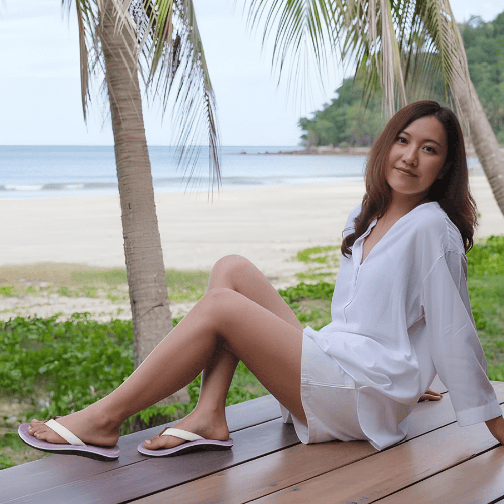 Woman in a white outfit sitting on a wooden bench by a beach with palm trees.
plantar fasciitis sandals​
sandals for plantar fasciitis​
best sandals for plantar fasciitis​